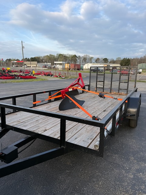Utility trailer loaded with a farm plow on a dealer lot