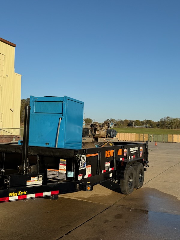 Raiders Trailer Rental dump trailer loaded with a blue air compressor unit